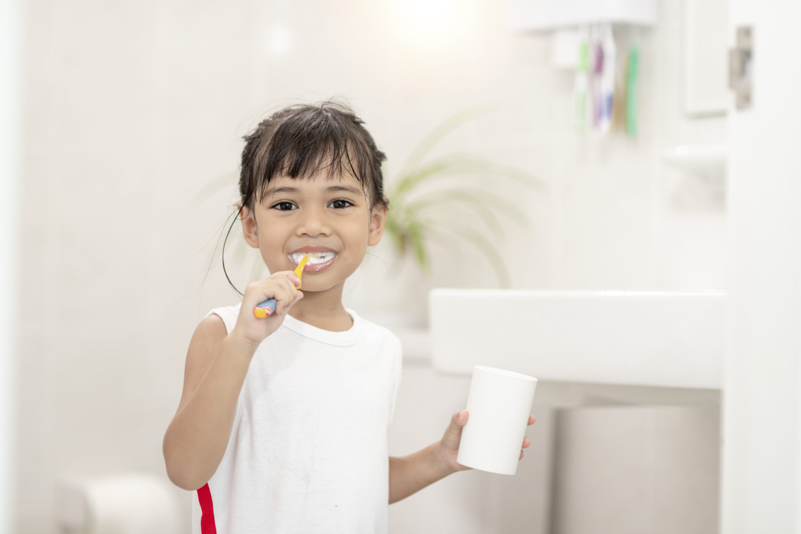 Little cute baby girl cleaning her teeth with a toothbrush in the bathroom